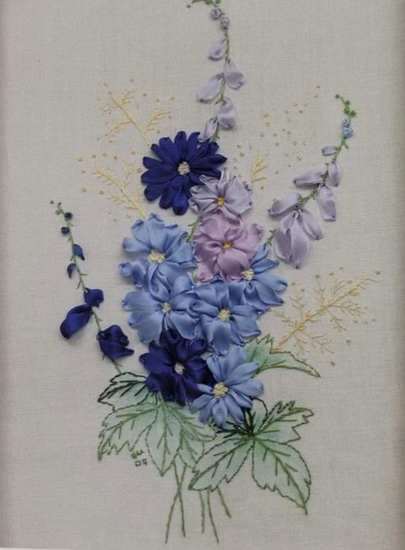 Tall blue and lilac delphiniums worked in silk ribbon on pale linen, with fine green leaves stitched beneath