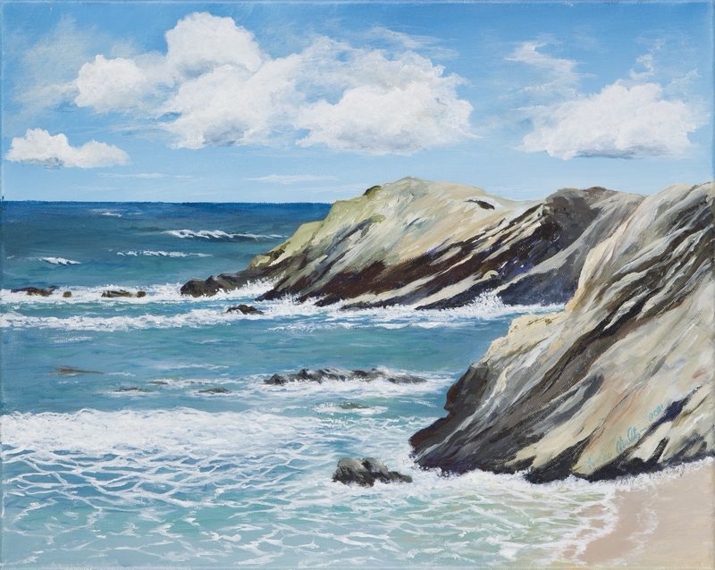 Waves rolling into a rocky cove under a bright blue summer sky